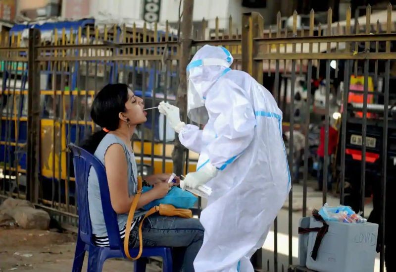 A health worker wearing a PPE kit collects a sample from a woman for the COVID-19 Rapid Antigen Test, at a city market in Bengaluru.(PTI)